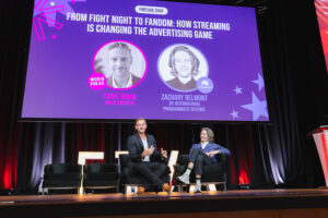 Panel discussion on a purple stage banner:'From Fight Night to Fandom: How Streaming Is Changing the Advertising Game' with two speakers on chairs behind them