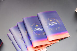 Several copies of a purple-to-orange gradient booklet titled'VOD Evolution 2021 Study' stacked on a dark desk in a fan-shaped arrangement.